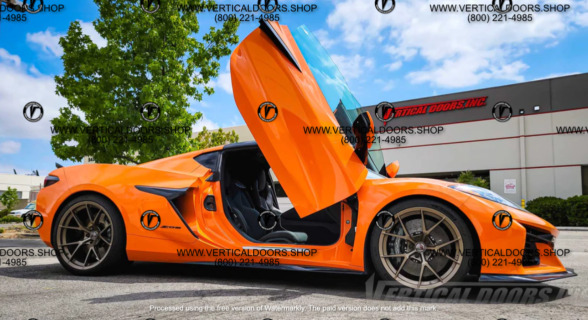 Orange sports car with C8 Z06 vertical door kit installed showing open scissor style doors