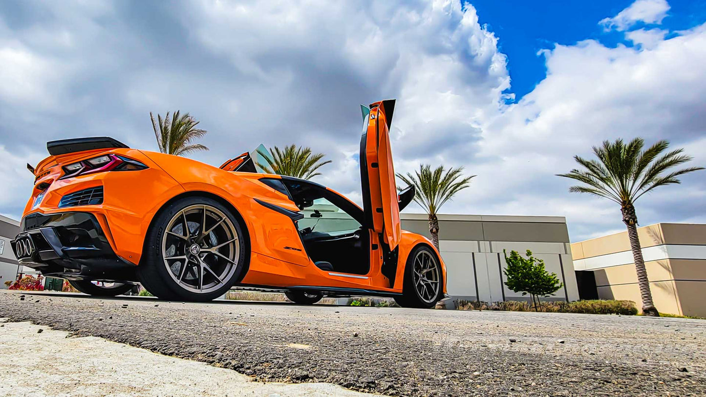 Orange C8 Z06 sports car with black accents featuring C8 Z06 vertical door kit open outdoors