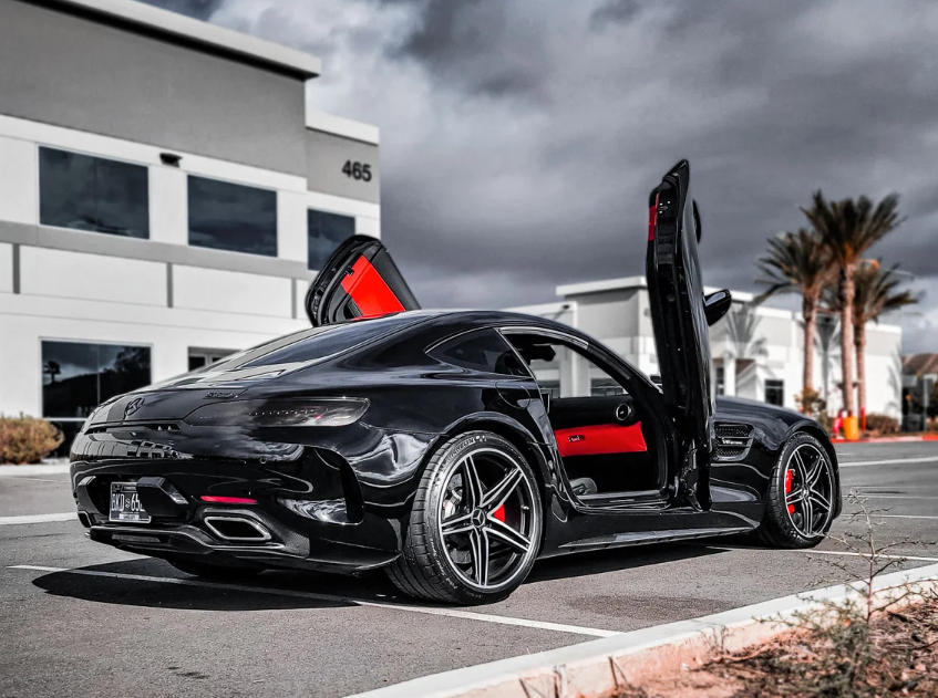 Black Mercedes AMG GT with red interior featuring Mercedes AMG GT lambo doors kit installed outside modern building
