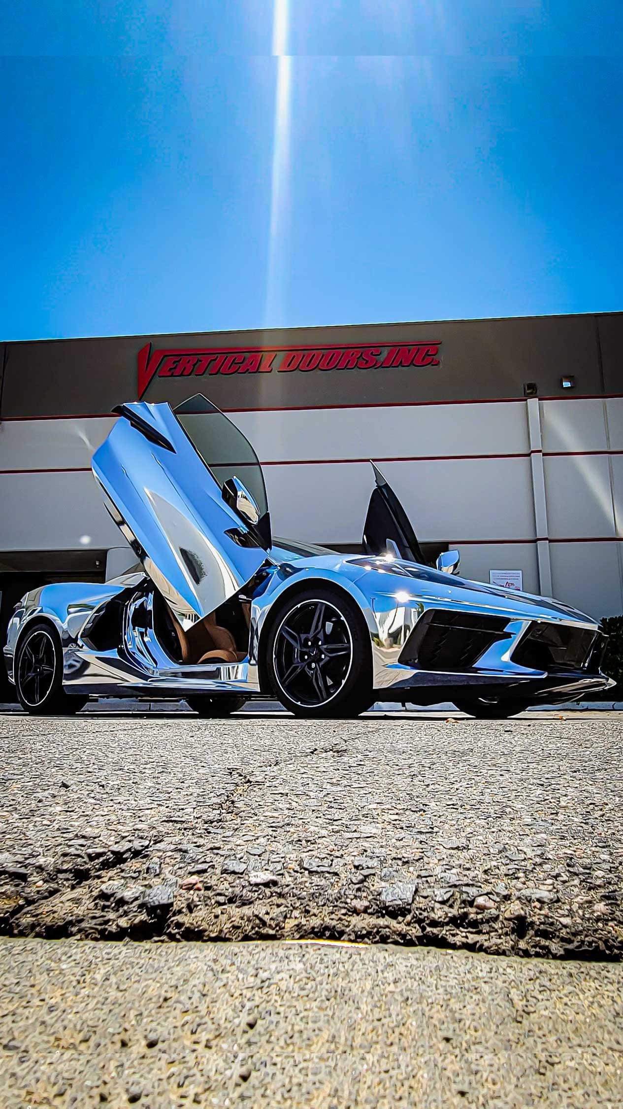 Silver C8 Corvette with Vertical Doors Inc C8 Corvette Lambo door kit installed outside building