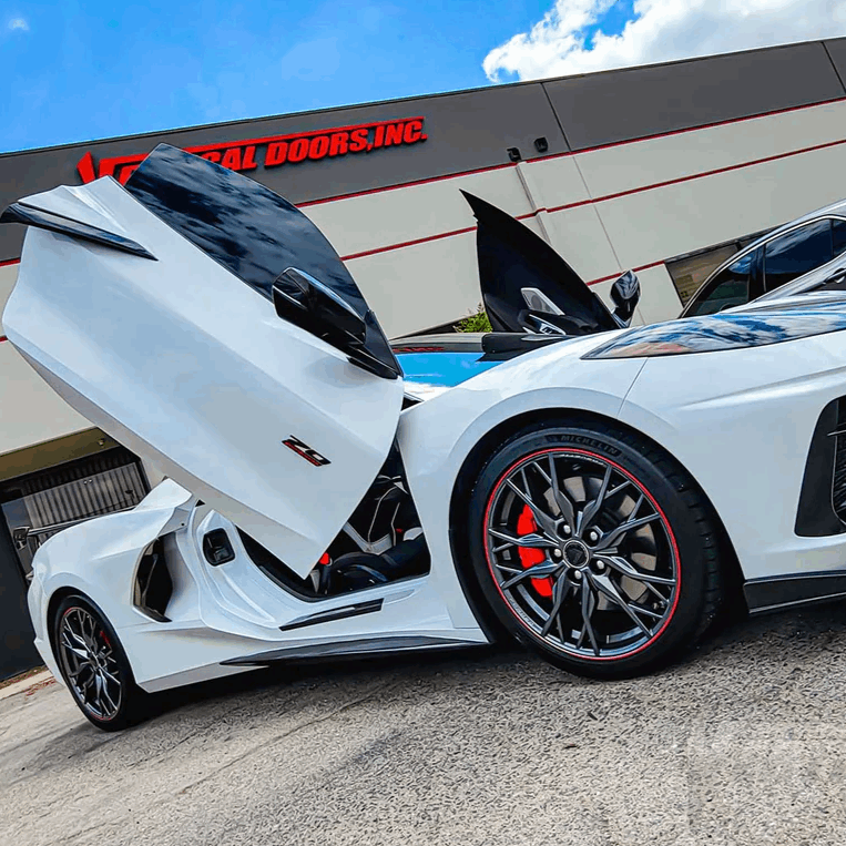 White sports car with C8 vertical doors at-home installation outside Vertical Doors Inc building