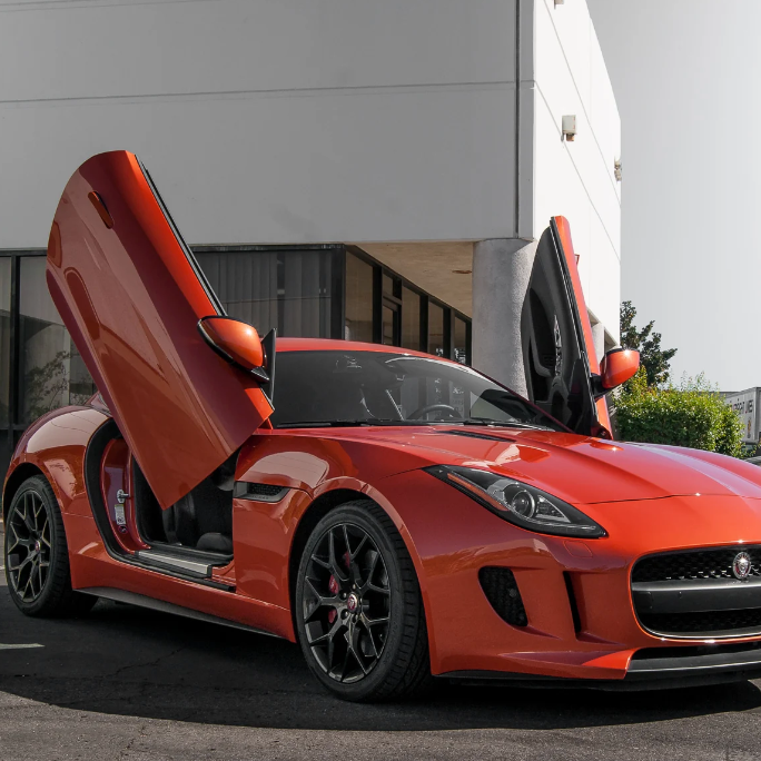Red Jaguar F-Type sports car with Jaguar F-Type Lambo doors kit installed in an open position