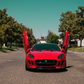 Red Jaguar F-Type with installed Jaguar F-Type Lambo doors kit open on both sides on a sunny street
