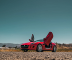 Red Jaguar F-Type sports car with Jaguar F-Type Lambo doors kit installed open on a sunny day