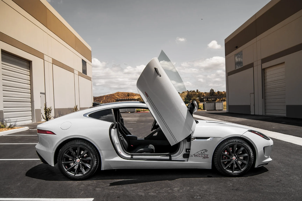 White Jaguar F-Type with Jaguar F-Type Lambo doors kit installed in urban parking lot