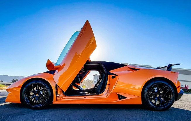 Orange sports car with open vertical doors featuring Huracan Lambo door kit by Vertical Doors Inc