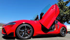 Red Toyota Supra Mk5 with Vertical Doors Inc Toyota Supra Mk5 Lambo Doors open under clear blue sky