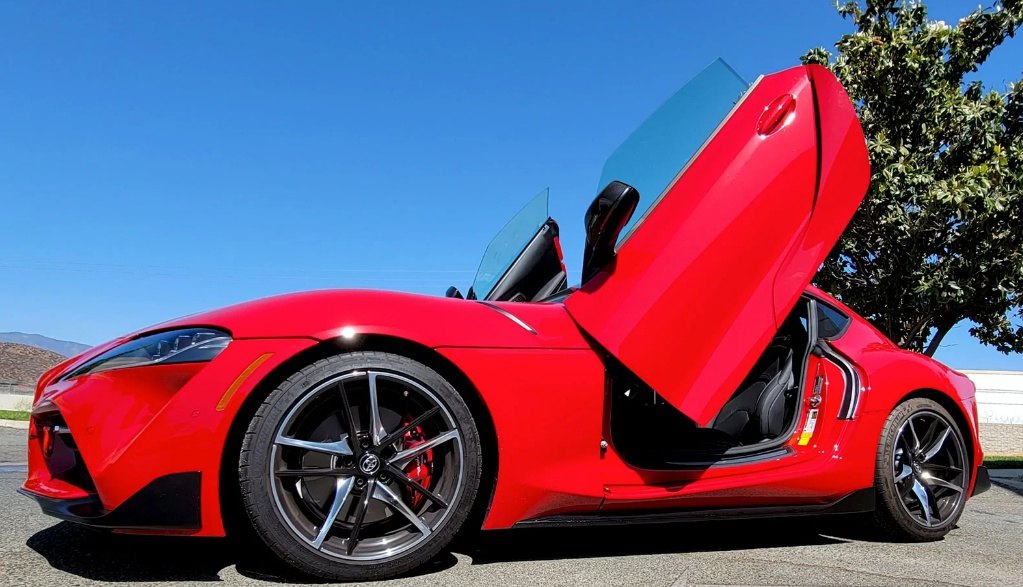 Red Toyota Supra Mk5 with Vertical Doors Inc Toyota Supra Mk5 Lambo Doors open under clear blue sky