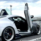 White Toyota Supra Mk5 with black custom Toyota Supra Mk5 Lambo Doors open in parking lot