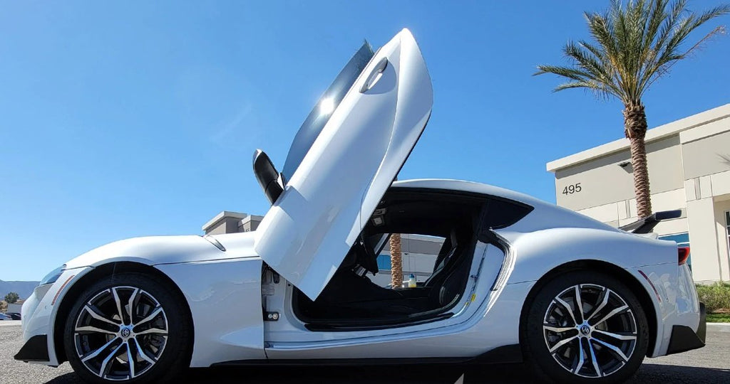 White Toyota Supra Mk5 with Vertical Doors Inc Toyota Supra Mk5 Lambo Doors open in outdoor setting